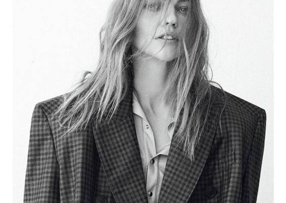 Photographed in black and white, Sasha Pivovarova wears Balenciaga plaid coat and button-up shirt